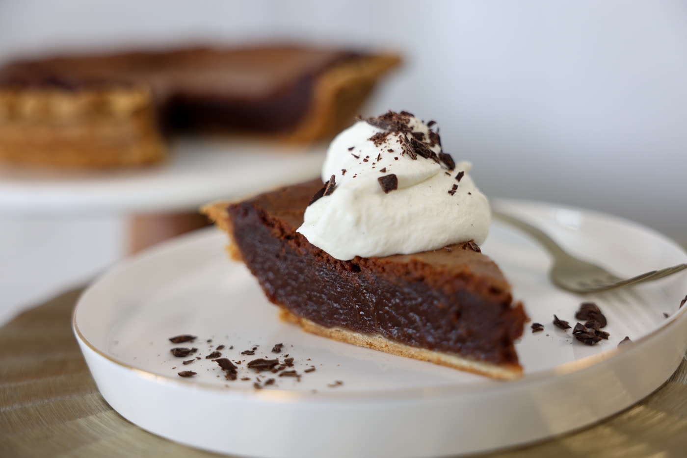 Slice of chocolate chess pie topped with whipped cream and chocolate shavings